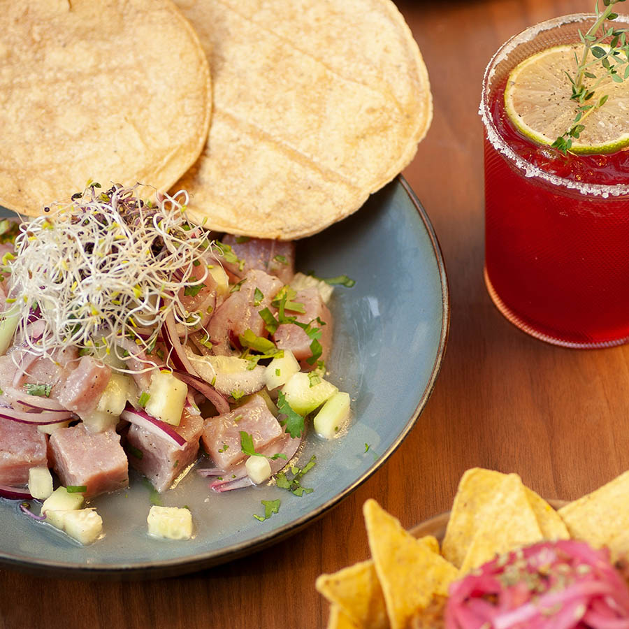 Mexican food including chips and salsa and tortillas on plates with cocktail.