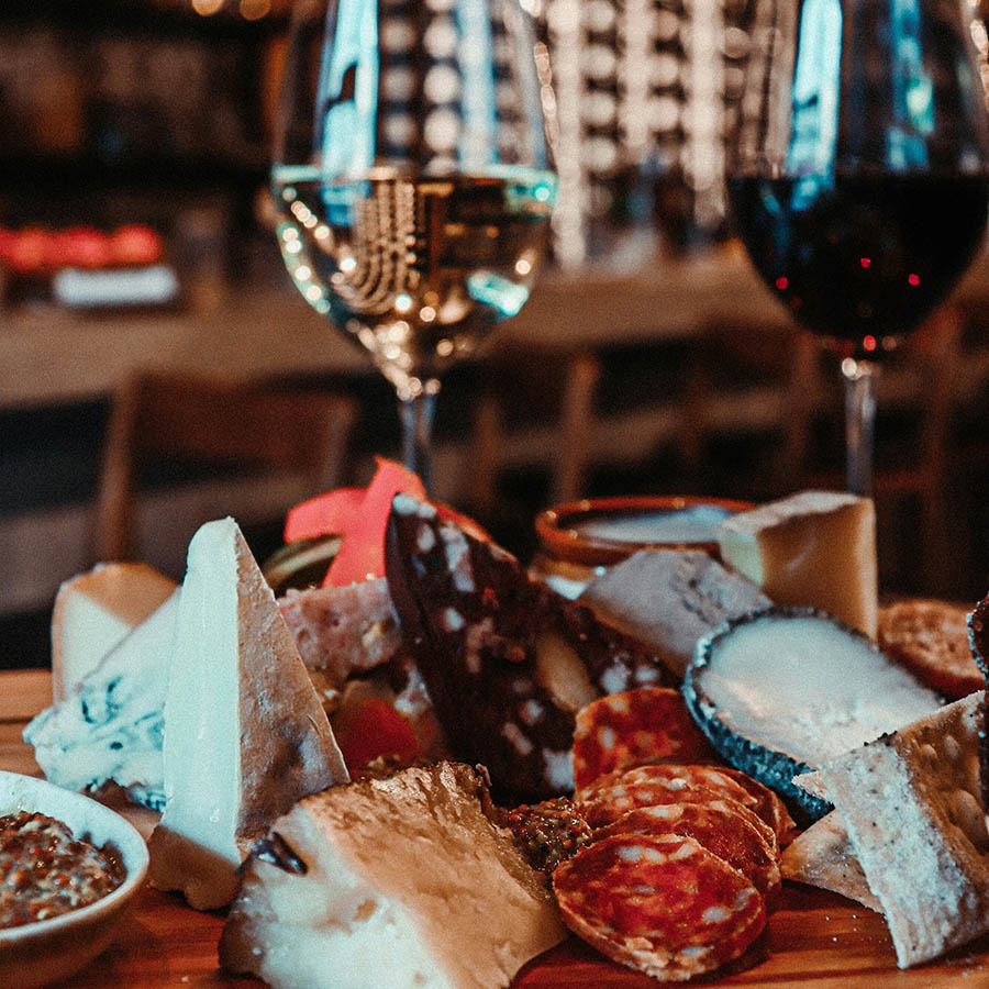 Charcuterie board with meats, cheeses, and glasses of wine.