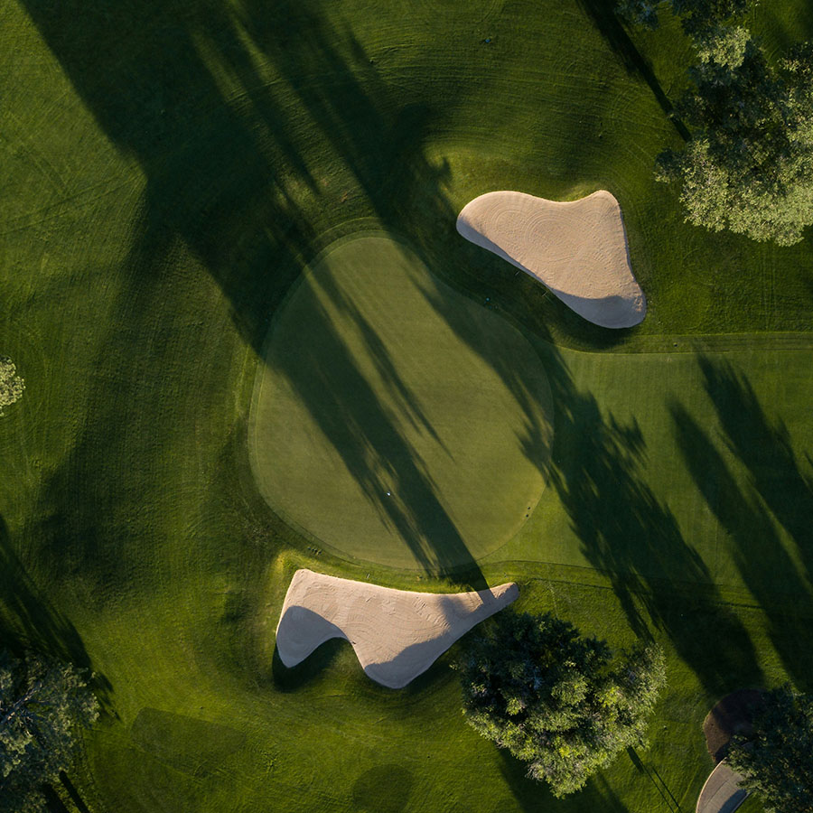 Aerial view of golf course with manicured greens and sandy bunkers.