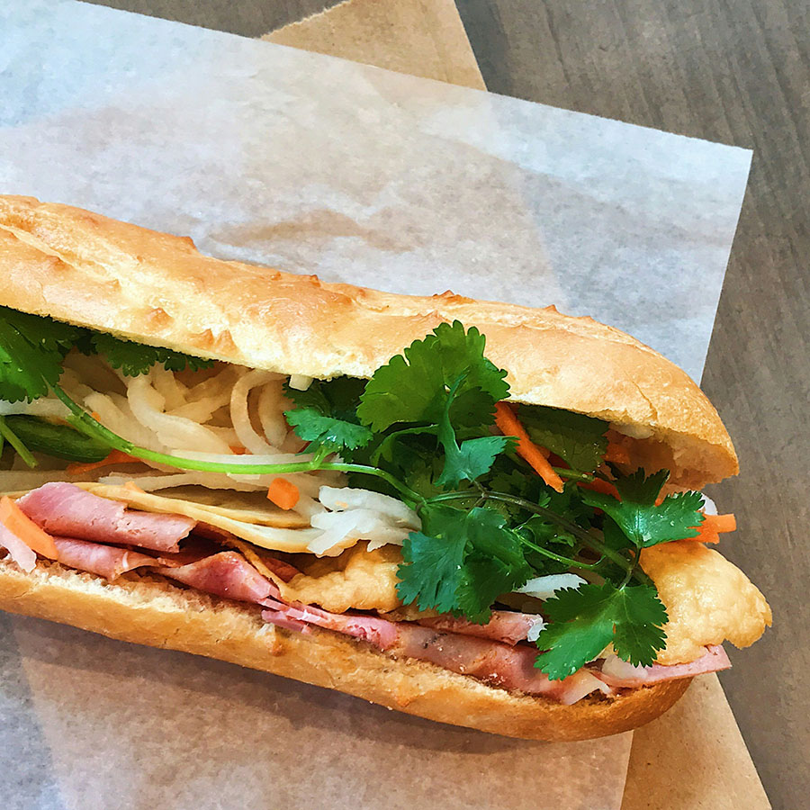 Deli sandwich with meat and vegetables on table.