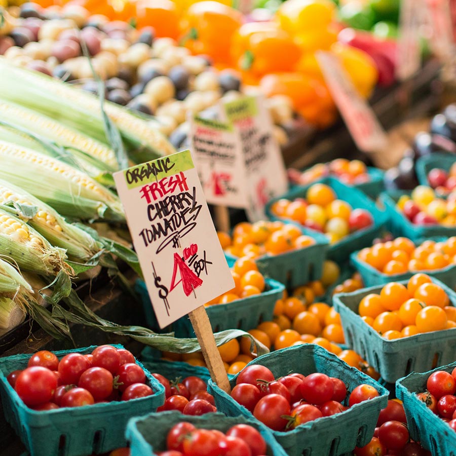 Produce stand with fresh corn, tomatoes, and peppers.