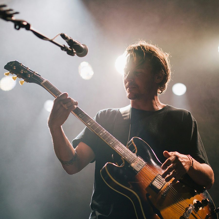 Person on stage playing electric guitar.
