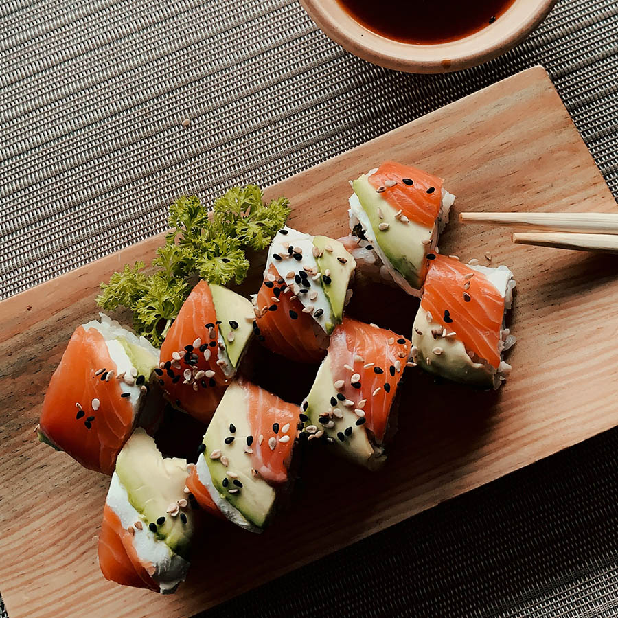 Table with sushi rolls, chop sticks, and bowl of soy sauce.