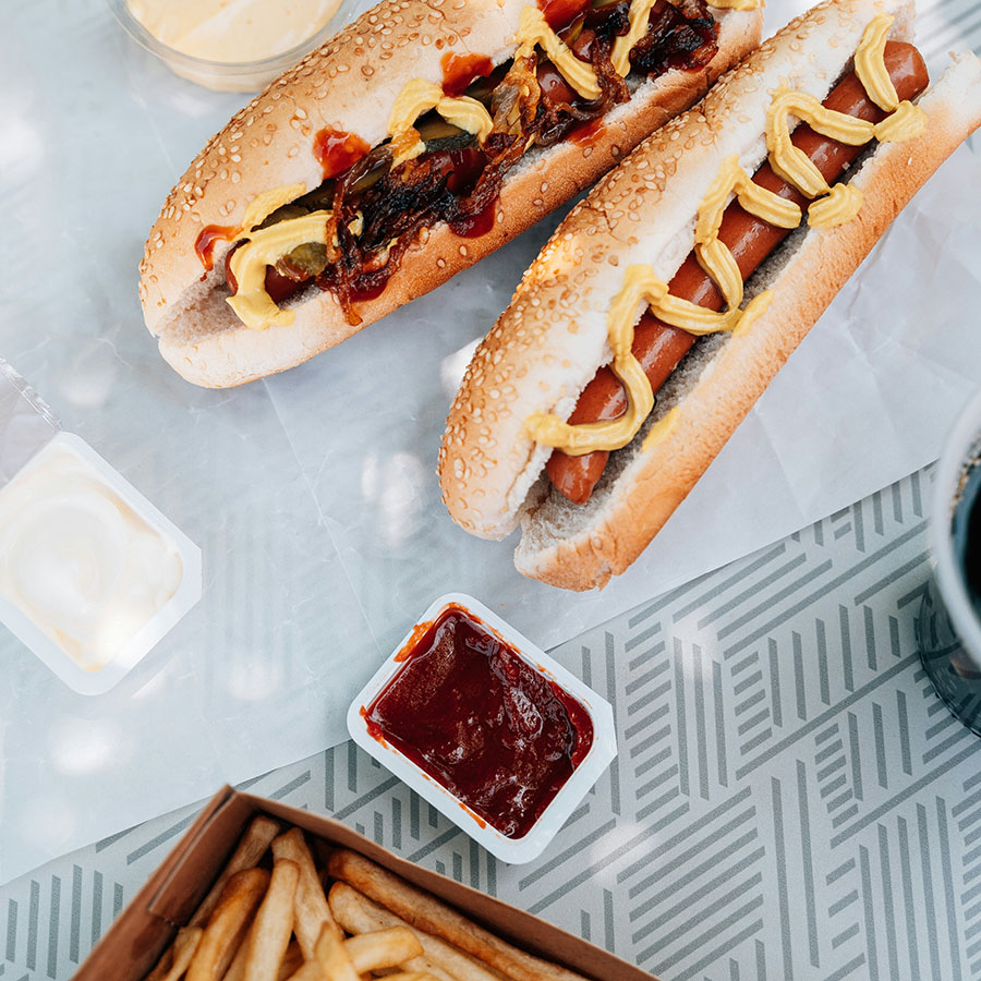 Table with french fries and fully loaded hot dogs.