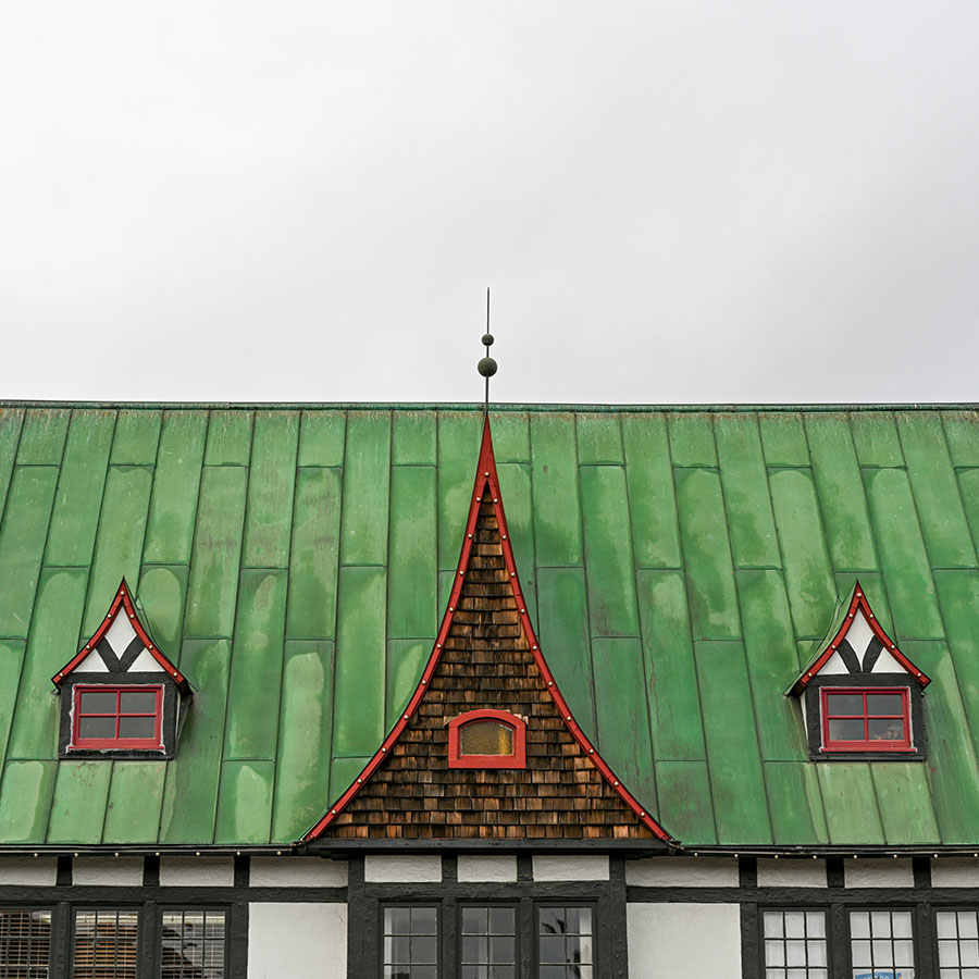 Eclectically-designed building with green roof and red accents.
