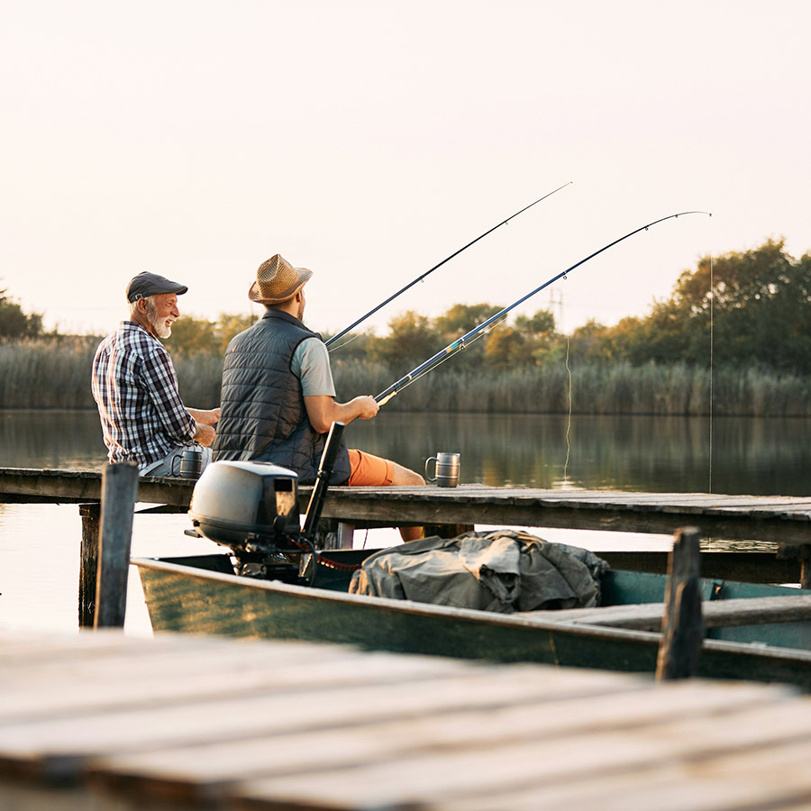 Two friends sitting together on dock fishing.