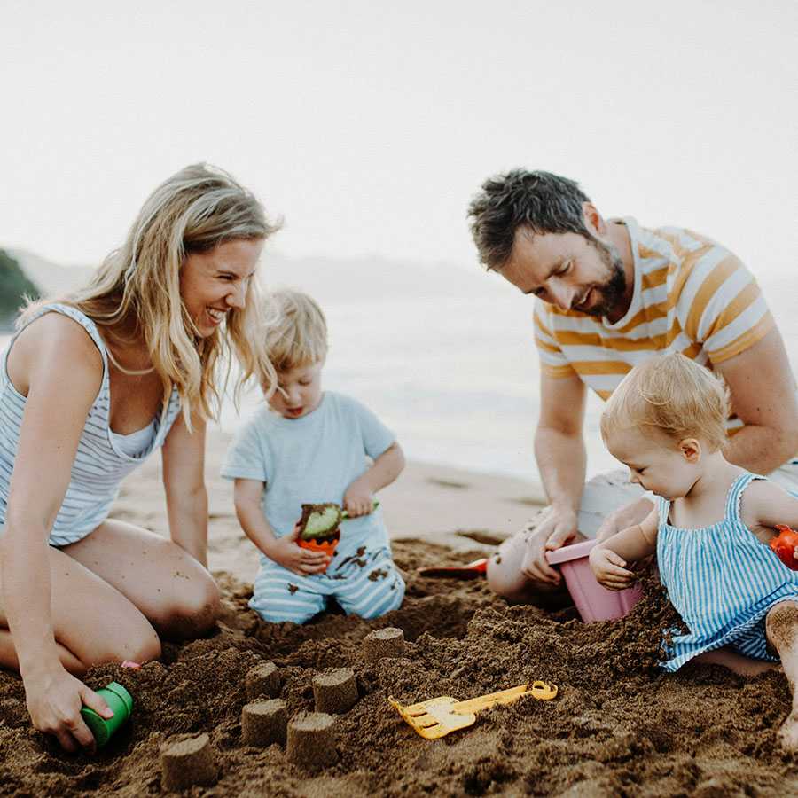 Young family playing together on a sandy beach.