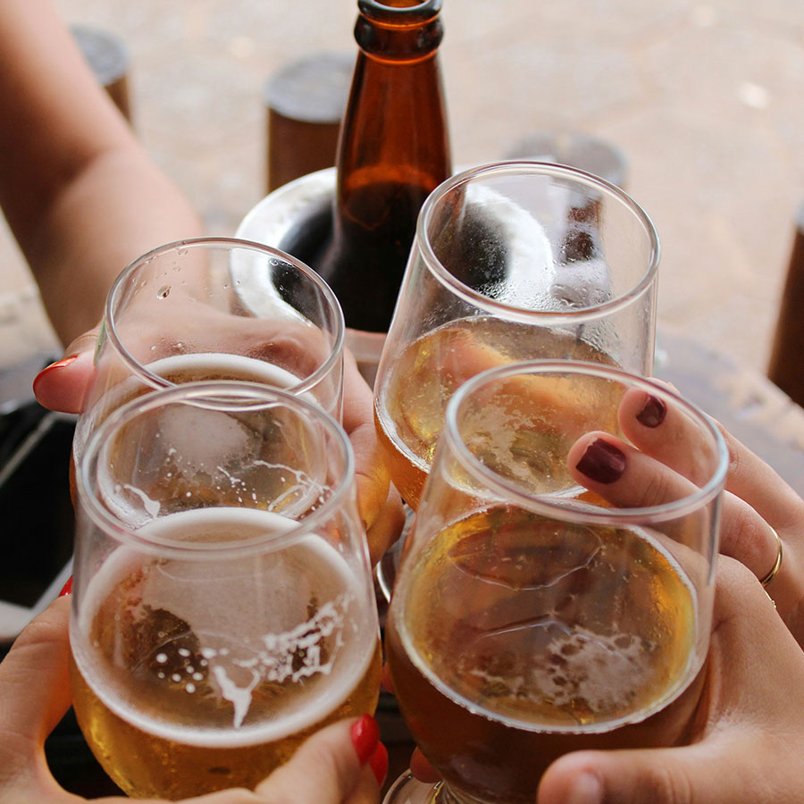 Friends toasting with beers at outdoor brewery.