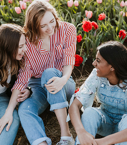 Friends sitting together in field of bright flowers.