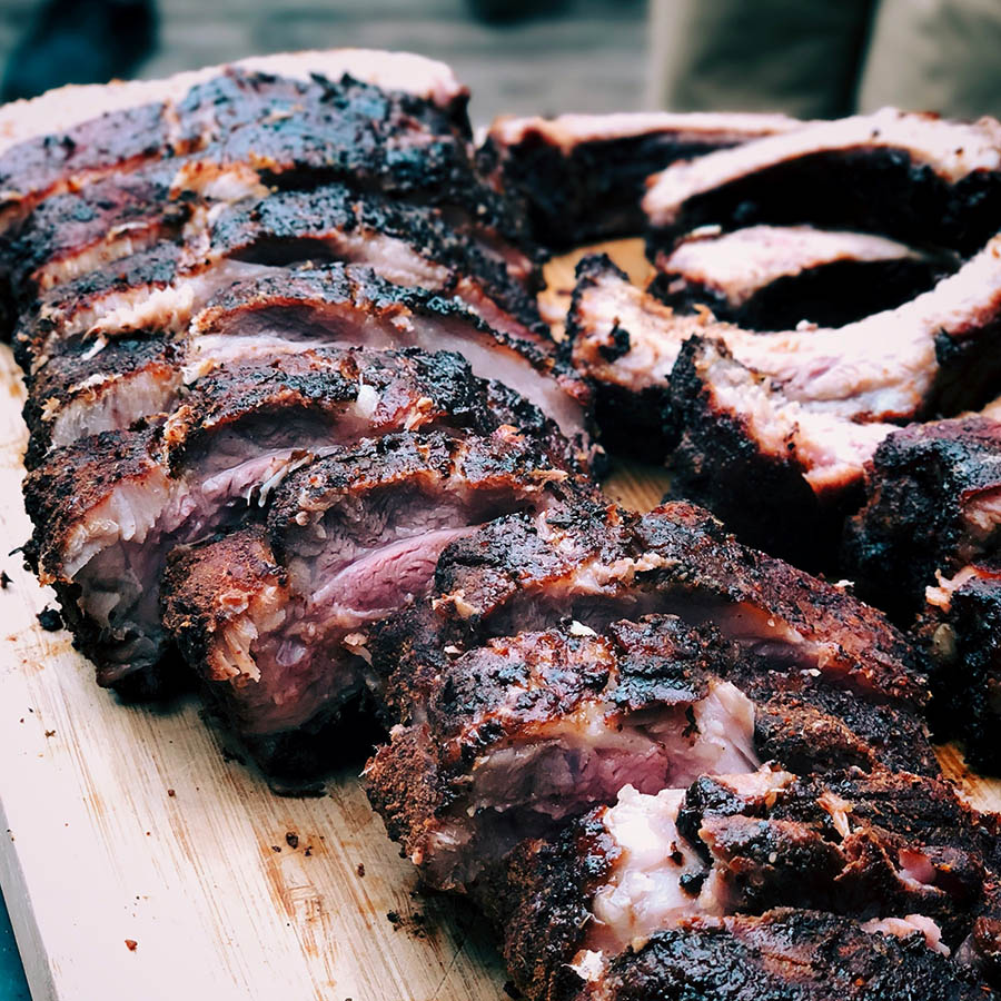 Sliced BBQ ribs on a wooden platter.