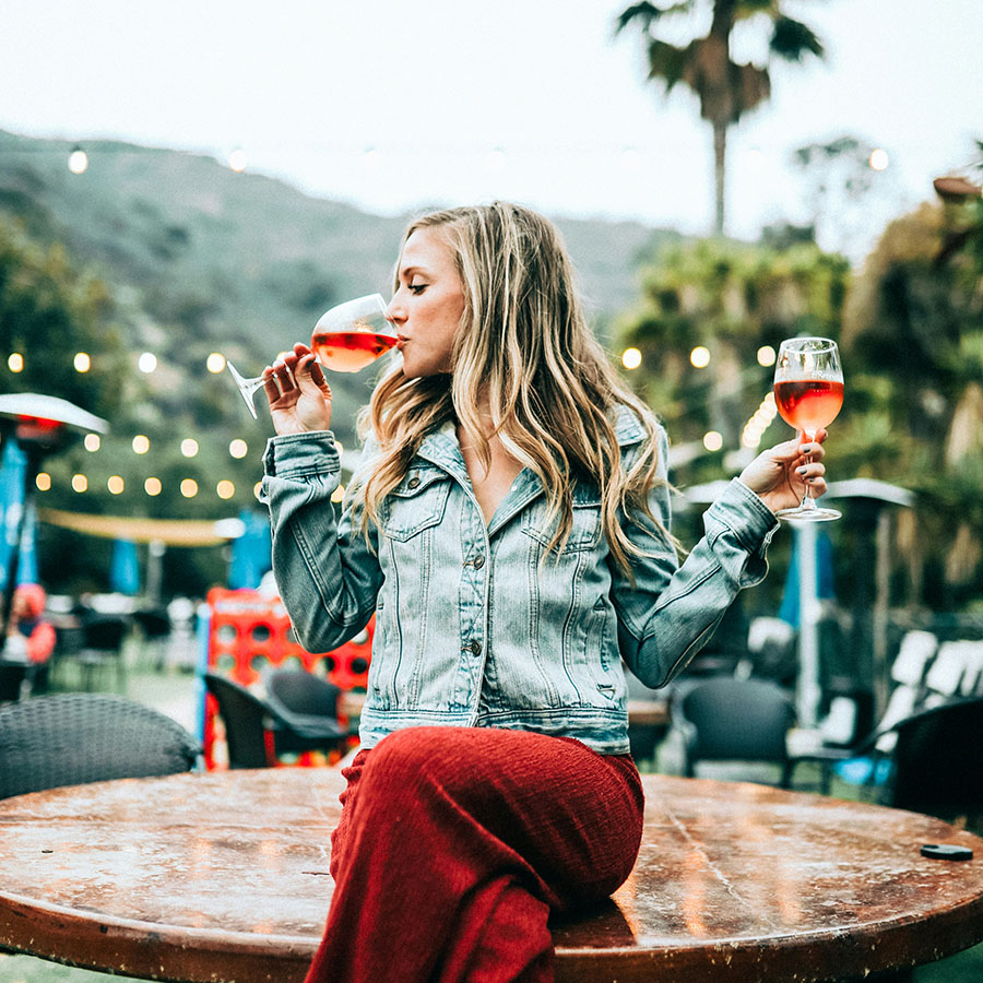 Person sitting on table at outdoor winery drinking wine.