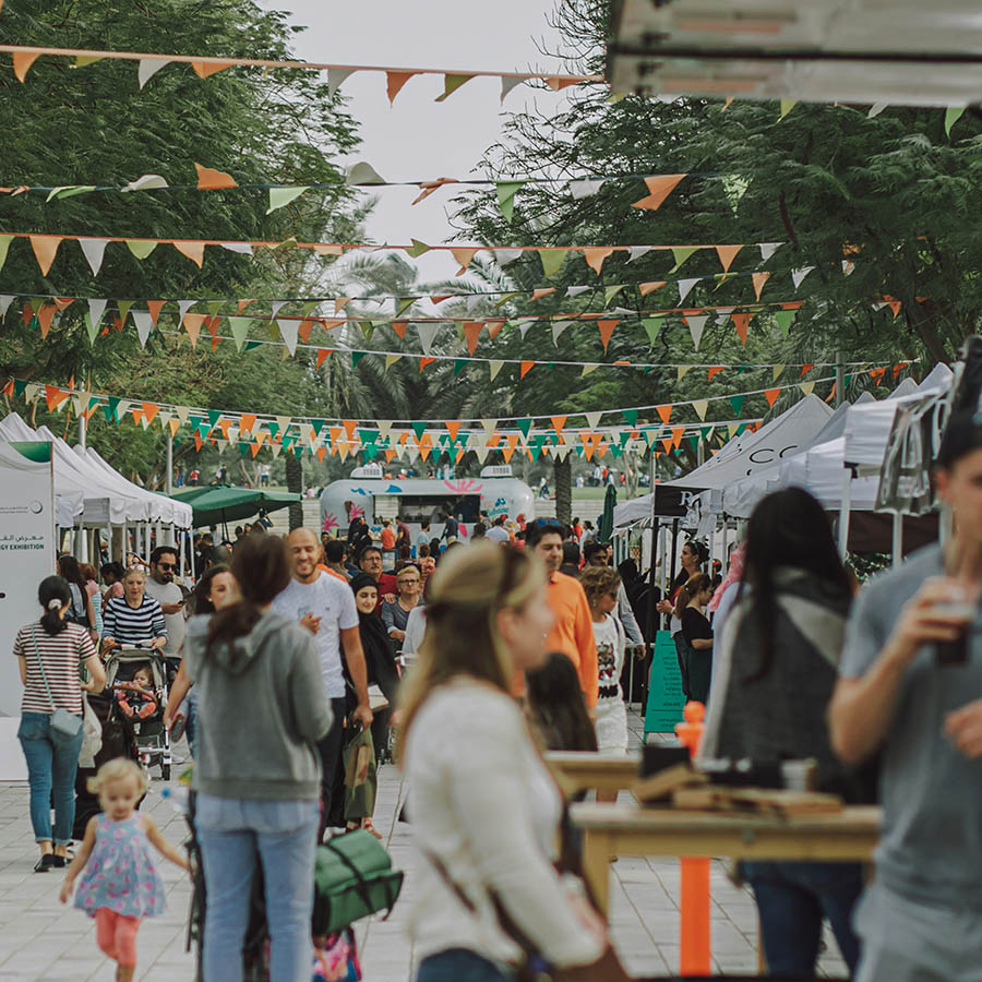 Avocado festival bustling with people shopping at stands under banners.