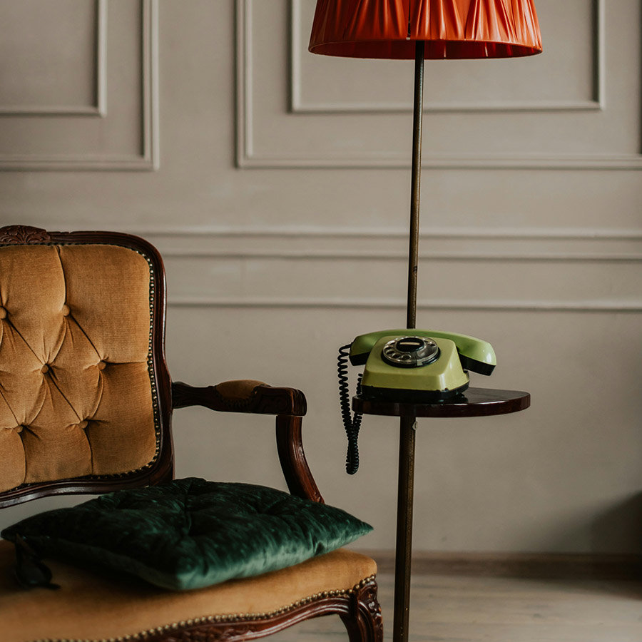 Elegant sitting area with plush chair, table with phone, and tall lamp.