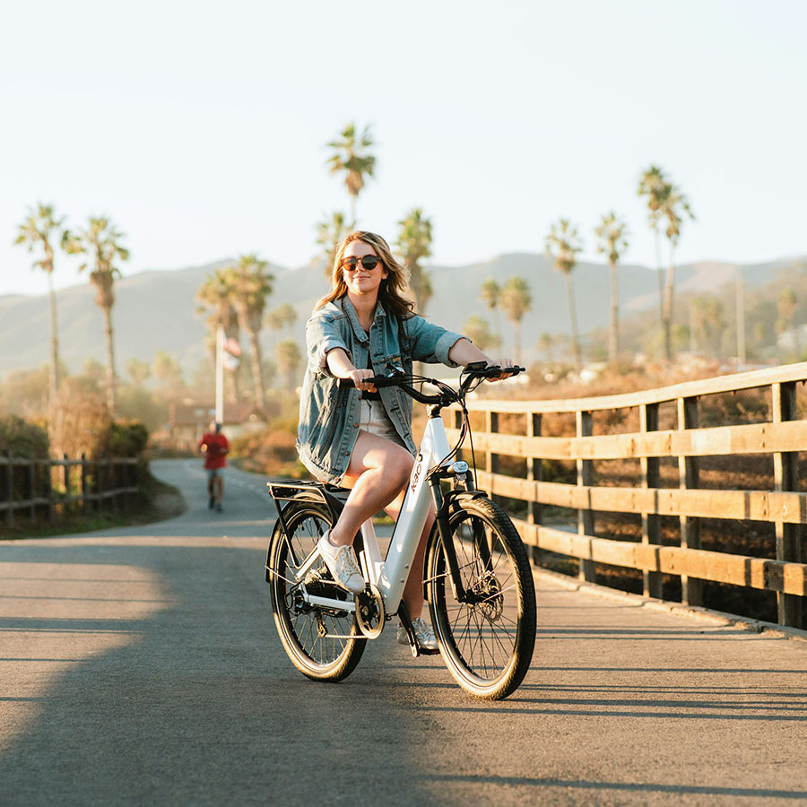Person on electric bike posing on wooden bridge in the sunshine.