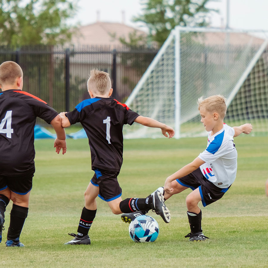 Children playing soccer on grassy field.