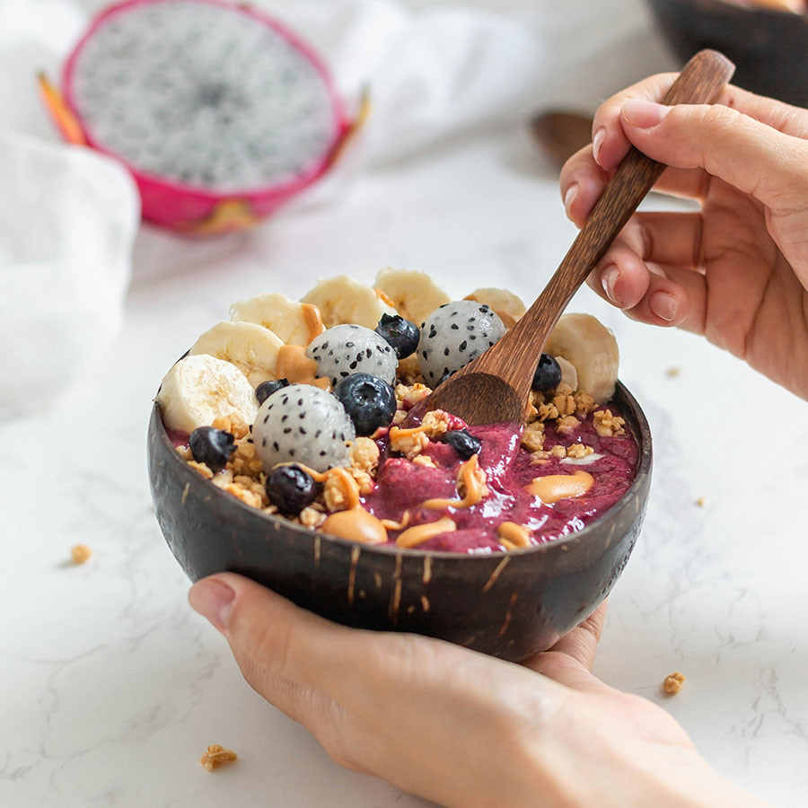 Person holding fresh and colorful acai bowl.