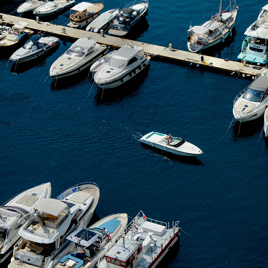 Marina filled with boats on dark blue ocean water.