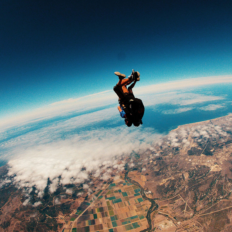 Two people skydiving from high above the Earth.