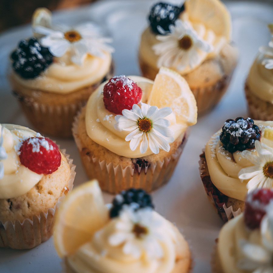 Elegantly decorated cupcakes with fruit and flowers.