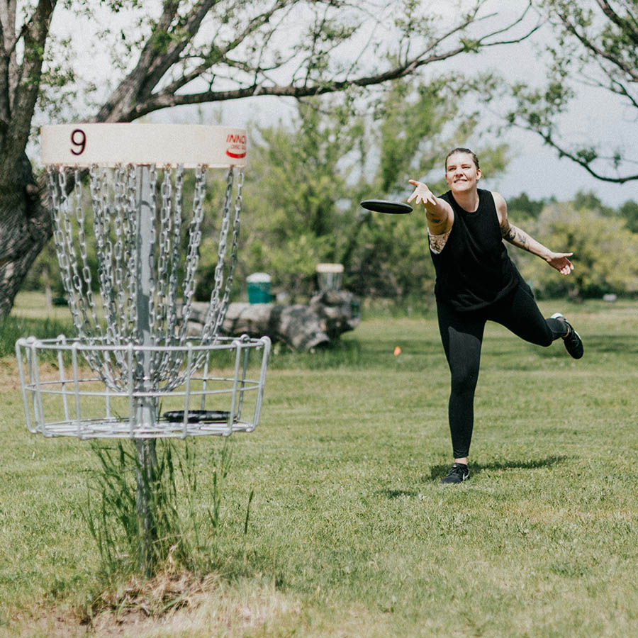 Person playing frisbee golf at grassy outdoor course.