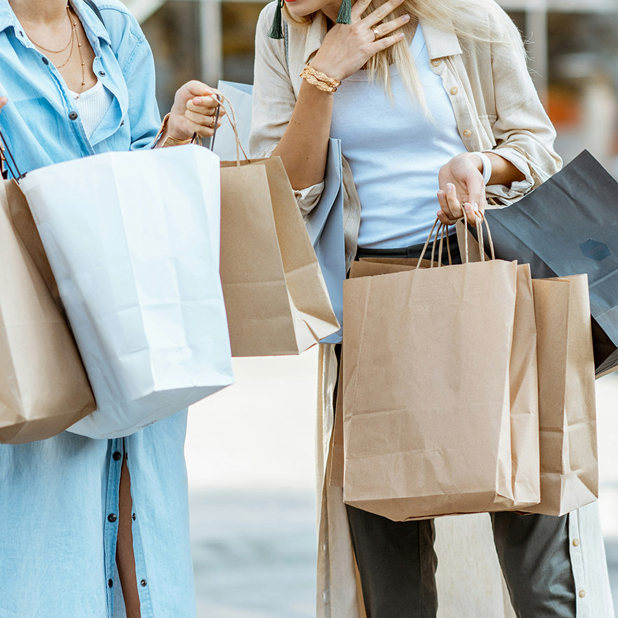 People holding shopping bags at outdoor mall.