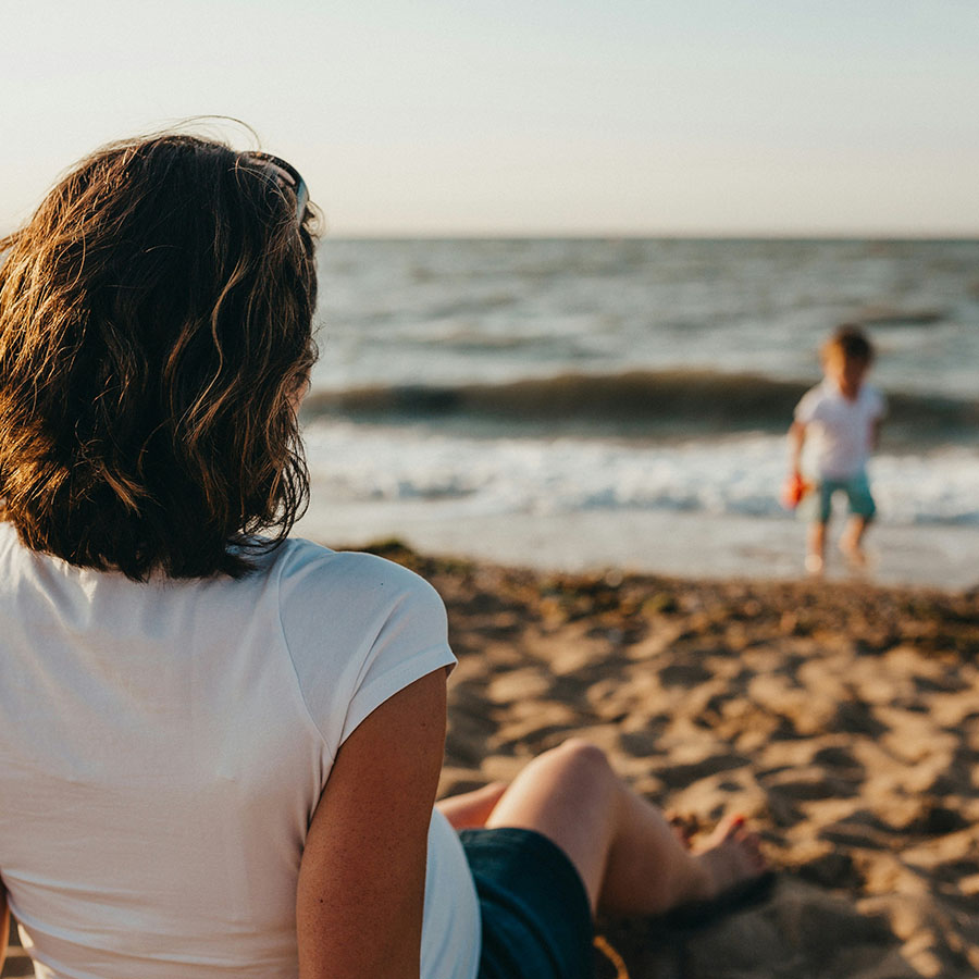 Parent and child playing together on sandy beach.